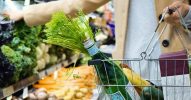 Person in einem Supermarkt, die einen Korb mit frischen Lebensmitteln hält.